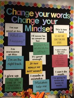 a bulletin board with words on it and flowers in vases sitting next to it