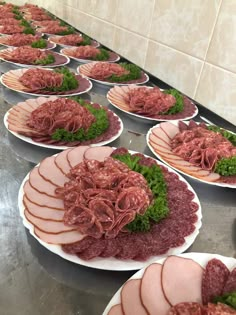 several plates filled with meat and vegetables on top of a metal counter in a kitchen