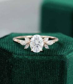 a diamond ring sitting on top of a green velvet box