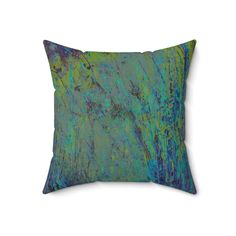 a blue and green pillow on a white background with an abstract painting in the middle