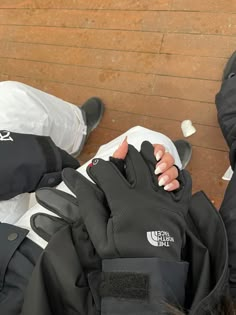 the north face gloves are laying on top of someone's back and their hands resting on them