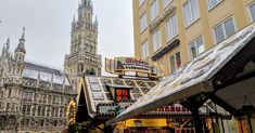 an outdoor market in front of a tall building with a clock tower on it's side