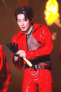 a man in red leather clothes holding a yellow plastic object and looking down at it