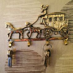 a horse drawn carriage with keys hanging from it's side on a wall next to a key holder