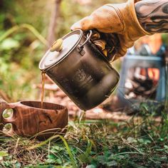 a person pouring tea into a cup in the woods