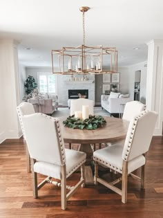 a dining room table with white chairs and a chandelier hanging from the ceiling