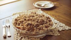 a pie sitting on top of a wooden table next to a fork and silverware