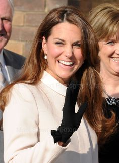 the woman is wearing black gloves and smiling at the camera while standing next to other people