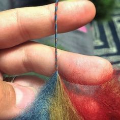 someone is stitching the ends of two different colored pieces of yarn on their fingers