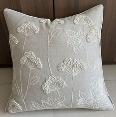 a pillow with white flowers on it sitting next to a wooden cabinet and cupboard door