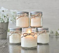 four mason jars filled with candles sitting on top of a table