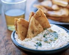 dip with pita chips on the side and glasses of beer in the background at a restaurant