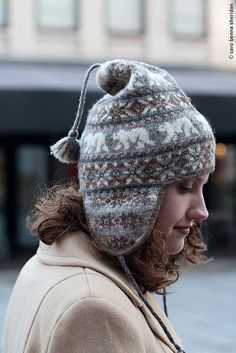 a woman wearing a knitted hat while looking at her cell phone in the street