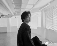 a young man sitting on the floor in an empty room looking at something off to the side