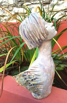 a statue of a woman's head sitting on top of a red brick wall