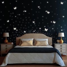 a bed sitting under a night sky filled with white butterflies on it's headboard