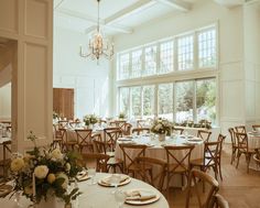 a room filled with lots of tables covered in white tablecloths and place settings