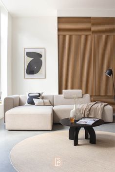 a living room with a couch, coffee table and large wooden paneled wall behind it