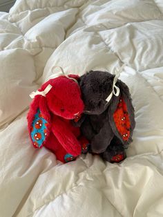 two stuffed animals sitting on top of a bed