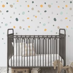 a baby's crib in front of a wall with polka dot decals