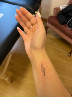 a woman's hand with a small lightning tattoo on her left wrist and an armband