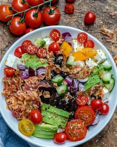 a salad with tomatoes, cucumbers, onions and other vegetables in a white bowl