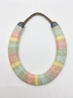 a multicolored necklace is hanging on a white wall with a wooden bead cord