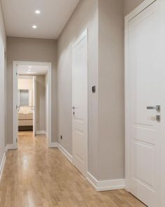 an empty room with white doors and hard wood flooring on the side of it