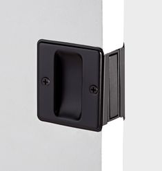 a black door handle on the side of a white wall with two square knobs