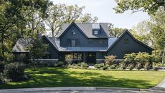 a large gray house surrounded by trees and grass