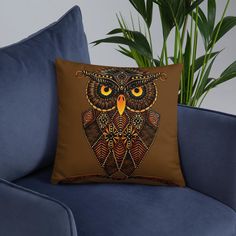 an owl pillow sitting on top of a blue couch next to a potted plant