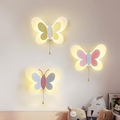 three butterfly shaped lights mounted to the side of a wall next to a teddy bear