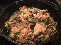 chicken and spinach stir fry in a wok on the stove top, ready to be cooked