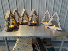 three wooden candles are sitting on a metal table with some wood pieces in front of it