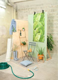 a room with plants and clothes hanging on the wall next to a ladder, potted plant