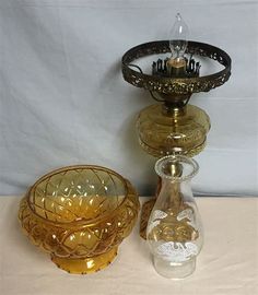 three glass bowls and a candle holder on a table with a white cloth behind them