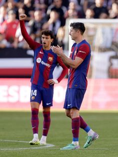 two soccer players standing on the field with their hands in the air and people watching