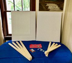 several pieces of wood sit on top of a blue table cloth with pegs in front of them