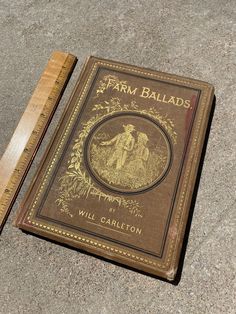 an old book is laying on the ground next to a ruler that says farm ballard