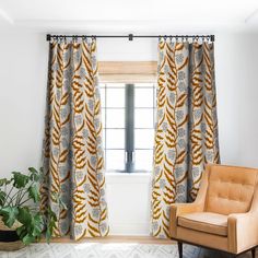 an orange chair sitting in front of a window next to a potted green plant