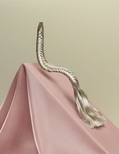 a pink umbrella with a tasseled handle on it's end and a rope attached to the top