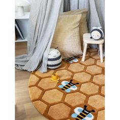 a round rug with two bees on it in front of curtains and a chair next to the bed