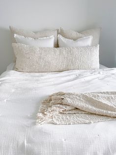 a bed with white linens and pillows on it