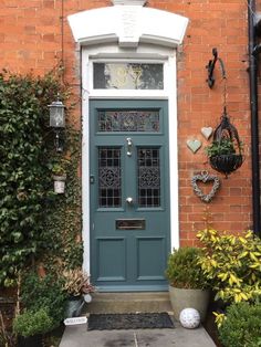 a blue front door on a red brick building with potted plants and hanging decorations