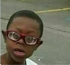 a young boy wearing red glasses and looking at the camera