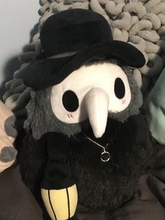 a stuffed bird wearing a top hat and holding a chain around its neck, sitting on a pile of pillows