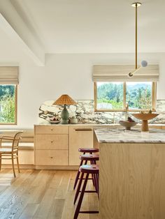 a kitchen with wooden floors and counter tops next to two stools in front of an island