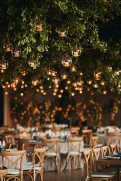 tables and chairs are set up for an event with lights hanging from the ceiling above them