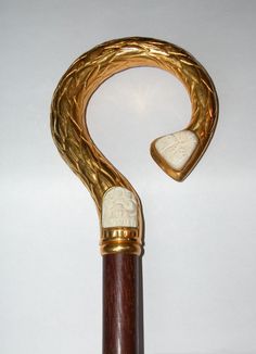 a gold and wood cane with an unusual handle on it's end, in the shape of a snake