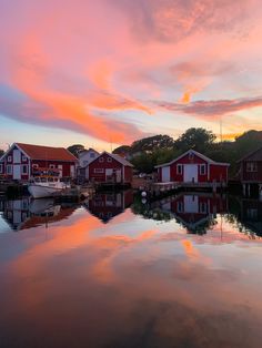 red houses are reflected in the still water at sunset, with pink clouds above them